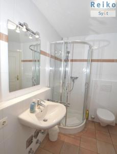 een witte badkamer met een douche en een wastafel bij Syltrose Whg 2 in Westerland