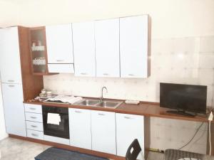 a kitchen with white cabinets and a sink and a tv at Studio with sea view furnished balcony and wifi at Marsala 1 km away from the beach in Marsala