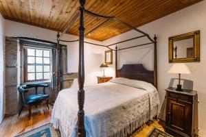 a bedroom with a canopy bed and a chair at Casa da Pedra Cavalgada in Braga