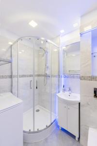 uma casa de banho branca com um chuveiro e um lavatório. em APARTAMENT PARKOWY UL. RACLAWICKA em Cracóvia