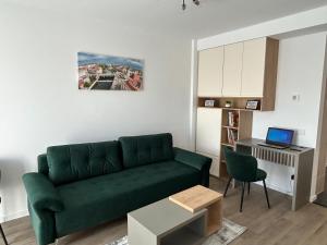 a living room with a green couch and a desk at Coquette Studio Central in Oradea