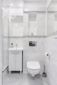 a white bathroom with a toilet and a sink at APARTAMENT PARKOWY UL. RACLAWICKA in Krakow