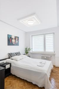 a white bedroom with a large bed and a window at APARTAMENT PARKOWY UL. RACLAWICKA in Krakow