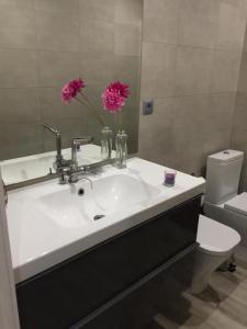 a bathroom with a sink with two pink flowers in a vase at Piso San Fernando centro in San Fernando
