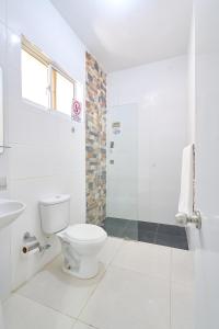 a white bathroom with a toilet and a shower at Red House on the beach in Punta Rucia