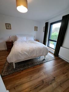 1 dormitorio con cama y ventana grande en Darrell Cottage, en Kanturk