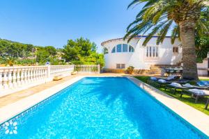 una piscina frente a una casa con palmeras en Villa Oasis by Abahana Villas, en Calpe