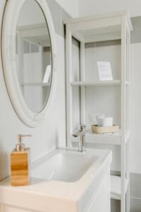 Baño blanco con lavabo y espejo en LA CASETTA Malpensa Guesthouse en Case Nuove