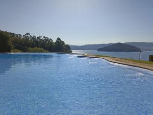 a large pool of blue water next to a lake at Chalet en Combarro a pie de playa in Poio