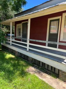 a house with a long porch on the grass at Wensel Cottage in downtown Natchez in Natchez
