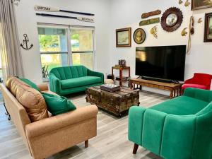 a living room with green furniture and a flat screen tv at Sanford's Seahaven in Sanford