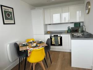 a kitchen with a table and yellow chairs in a kitchen at Stunning Old Trafford Apartment in Manchester