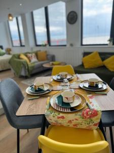 - une table avec des assiettes, des tasses et des chaises dans le salon dans l'établissement Stunning Old Trafford Apartment, à Manchester