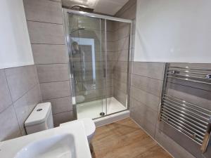 uma casa de banho com um chuveiro, um WC e um lavatório. em Stunning Old Trafford Apartment em Manchester