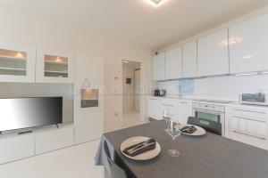 una cocina con armarios blancos y una mesa con platos. en Torre Mizar 11, en Lido di Jesolo