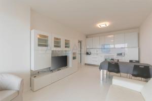 sala de estar blanca con mesa y sofá en Torre Mizar 11, en Lido di Jesolo