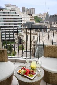 une assiette de fruits et des verres à vin sur une table sur un balcon dans l'établissement Hotel Sheltown, à Buenos Aires