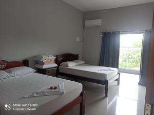 een kleine kamer met twee bedden en een raam bij Casa Familiar in Paraty