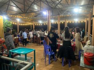 a group of people standing in a large room with tables at Pac Ngoi Village's homestay - Hoàng Nguyên in Bak Kan