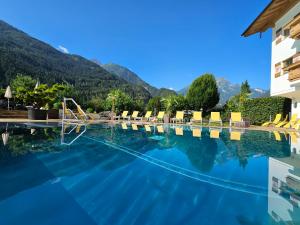 uma piscina com cadeiras e montanhas ao fundo em Hotel Edenlehen em Mayrhofen