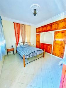 - une chambre avec un lit doté de draps bleus et de placards en bois dans l'établissement Appartement Vintage à EL JADIDA rte Sidi Bouzid, à El Jadida