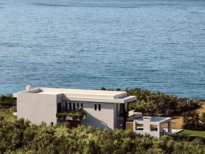 una casa blanca con el océano en el fondo en Oresteia Presidential Villa, a Legendary Retreat, By ThinkVilla, en Gaïtánion
