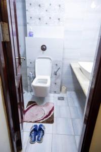 a bathroom with a toilet and a sink and blue shoes at Kitengule Apartment 001 in Dar es Salaam