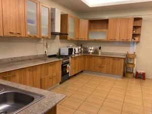 a large kitchen with wooden cabinets and a sink at Kitengule Apartment 001 in Dar es Salaam