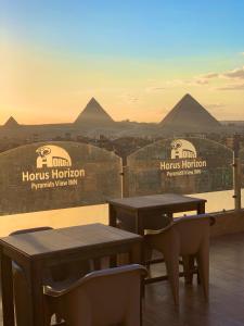 dos mesas y sillas en la parte superior de un edificio con pirámides en The Horizon Pyramids View en El Cairo