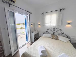 a white bedroom with a bed and a balcony at Pension Barbara in Katapola
