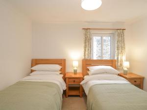two beds in a room with two lamps and a window at Fiddlers Pit Cottage in Great Malvern