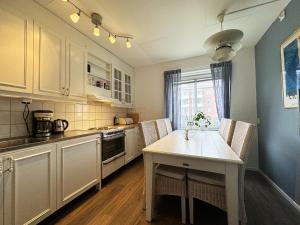 una cucina con armadi bianchi e tavolo con sedie di Nice, quiet apartment in central Karlstad a Karlstad