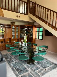 a dining room with a glass table and green chairs at Résidence Gabrielle in São Tomé