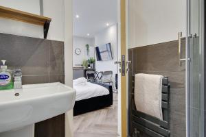 a bathroom with a sink and a bedroom with a bed at Wimbourne Road Apartment 1 in Bournemouth