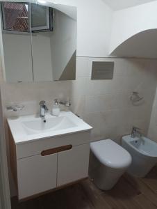 uma casa de banho branca com um lavatório e um WC em Divingreta 1820 em Ottaviano