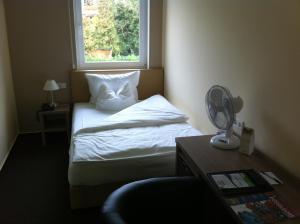 a bedroom with a bed with a window and a fan at Hotel Destination 21 in Düsseldorf