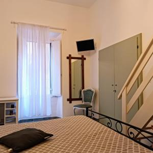 a bedroom with a bed and a chair and a mirror at La Casetta Nelle Mura in Terracina