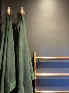 two green towels hanging on a rack in a bathroom at Cotswold Garden Cottage in Chipping Norton