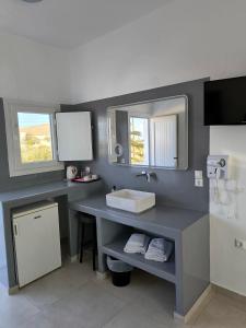 ein Badezimmer mit einem Waschbecken und einer Theke mit einem Spiegel in der Unterkunft Mary Rooms in Perivolos