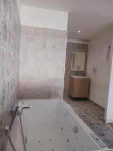 La salle de bains blanche est pourvue d'une baignoire et d'un lavabo. dans l'établissement Cotinga, à Villars-les-Dombes