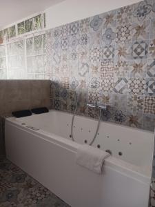 La salle de bains est pourvue d'une baignoire blanche et de carrelage. dans l'établissement Cotinga, à Villars-les-Dombes