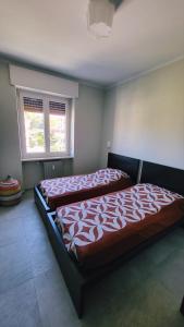 2 Betten in einem Schlafzimmer mit 2 Fenstern in der Unterkunft Appartamento SOAL in Monastero Bormida