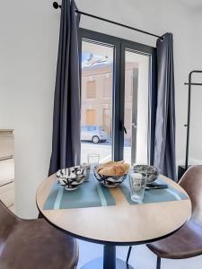 ein Esstisch mit Stühlen und ein Fenster in der Unterkunft La Licorne, grand studio chaleureux in Amiens