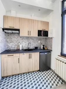 eine Küche mit Holzschränken und einem karierten Boden in der Unterkunft La Licorne, grand studio chaleureux in Amiens