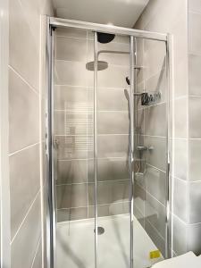 een douche met een glazen deur in de badkamer bij La Licorne, grand studio chaleureux in Amiens