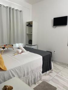 Habitación blanca con cama y TV de pantalla plana. en Estrela Premium Pousada en Gamboa