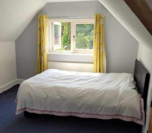 a bedroom with a bed with yellow curtains and a window at Victorian Gate House Own Bathroom in Solihull