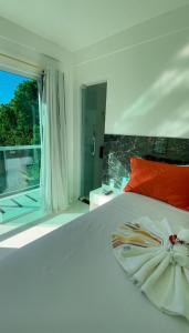 a bedroom with a white bed and a large window at Estrela Premium Pousada in Gamboa