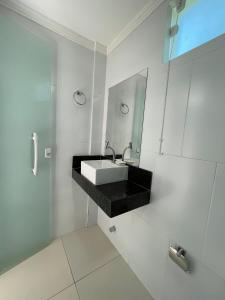 a white bathroom with a sink and a mirror at Estrela Premium Pousada in Gamboa