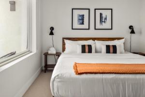 a bedroom with a white bed with an orange blanket on it at City Views - Lifestyle Loft - Zuni Lofts in Denver